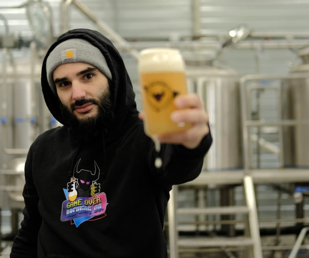 Romain, brasseur et fondateur de Game Over Brewing, tend un verre de bière dans la brasserie à Toulouse